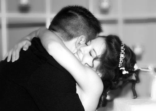 Black-and-white close-up of a bride embracing a groom with her eyes closed.